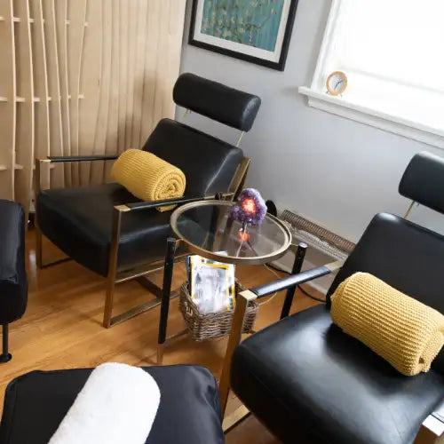 Black leather lounge chair with yellow throw blanket and glass coffee table.