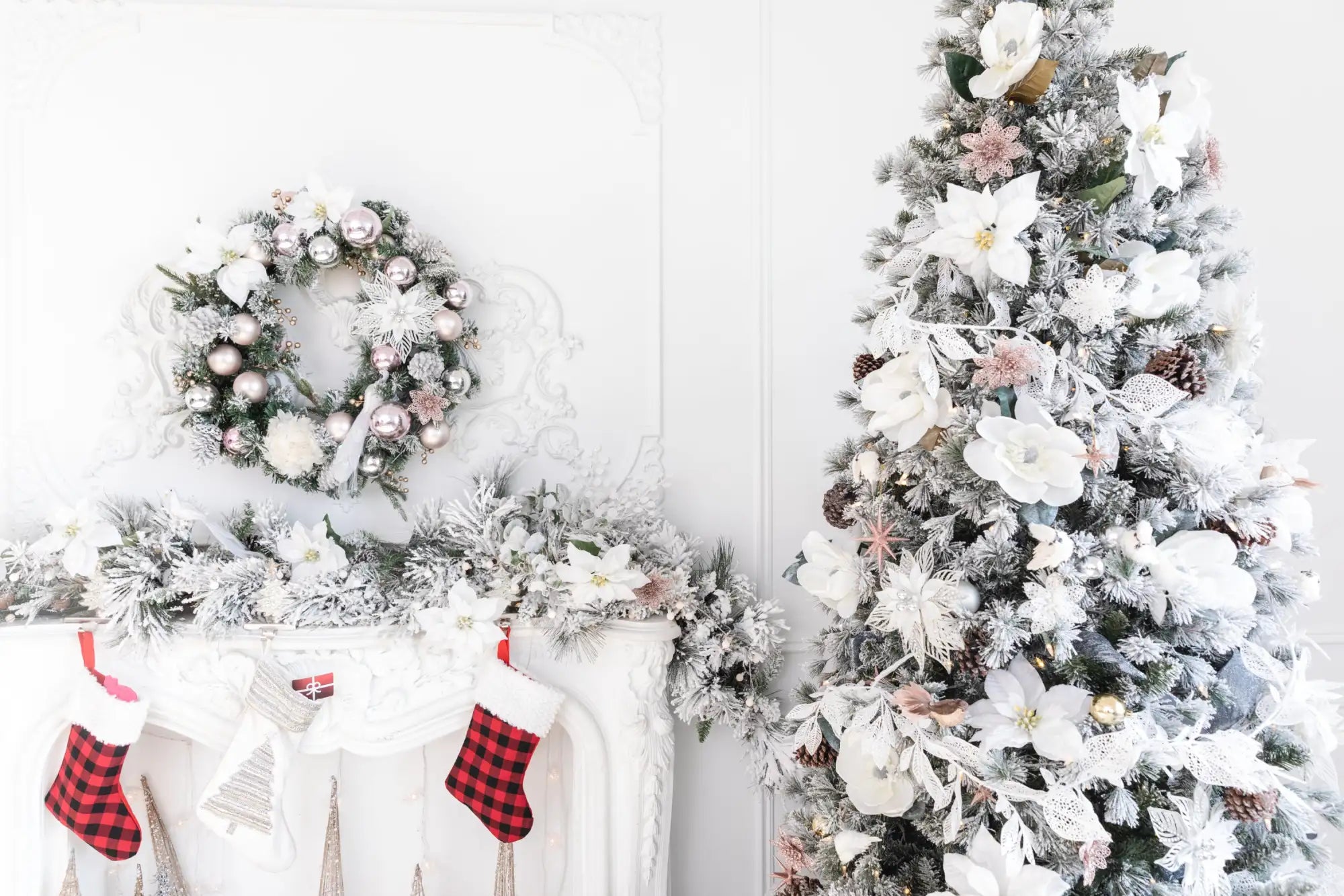 Frosty white christmas tree adorned with large white flowers, pink accents, and pinecones.